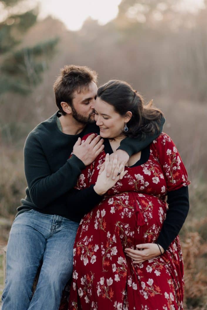 Parent to be are sitting in the field are cuddling each other. Maternity session outdoors. Hampshire photo shoot. Hampshire maternity photographer. Ewa Jones Photography