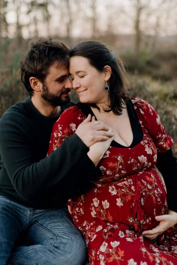 Mum and dad are sitting down and looking at each other. Maternity session outside in winter. Hampshire photo session. Ewa Jones Photography