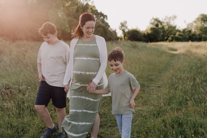 Mum to be and two sons are walking together at the fields. Happy family and maternity session. Hampshire photo shoot. Maternity photo shoot. Ewa Jones Photography