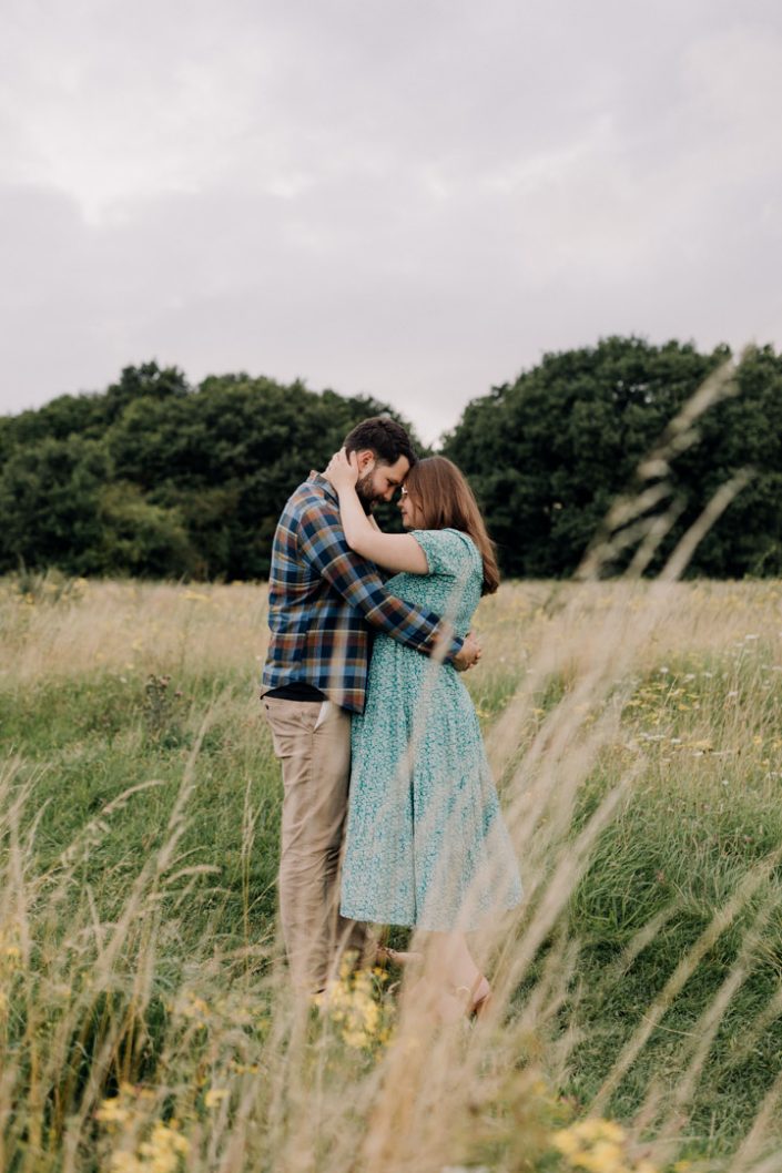 Mum to be is cuddling with her husband. Maternity photo session in the fields. Bump photo shoot in Hampshire. Outdoor maternity session. Ewa Jones Photography