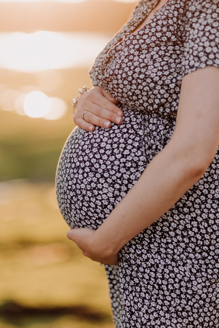 Close up of baby bump. Sun is shining at the back. Outdoor natural photo session in Hampshire. Ewa Jones Photography