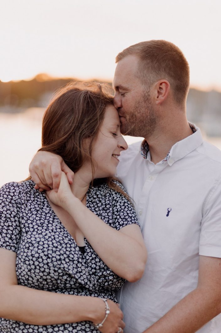 Mum and dad to be are cuddling and enjoying maternity photo session in Hampshire. What to wear for a family session. Black maternity dress and white t-shirt. Ewa Jones Photography