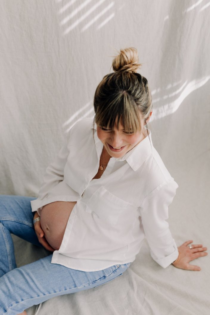 in home maternity photo session. Mum is wearing white shirt and jeans. Maternity shoot in Hampshire. Ewa Jones Photography