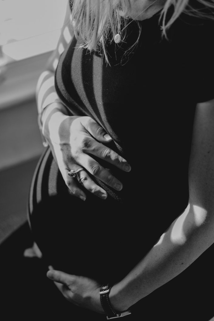 Black and white photograph of mum cuddling baby bump. In home intimate maternity session. Ewa Jones Photography