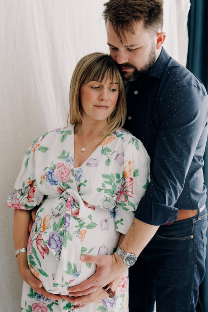 Mum and dad are standing and cuddling. Maternity poses at home. Hampshire and basingstoke photographer. Ewa Jones Photography