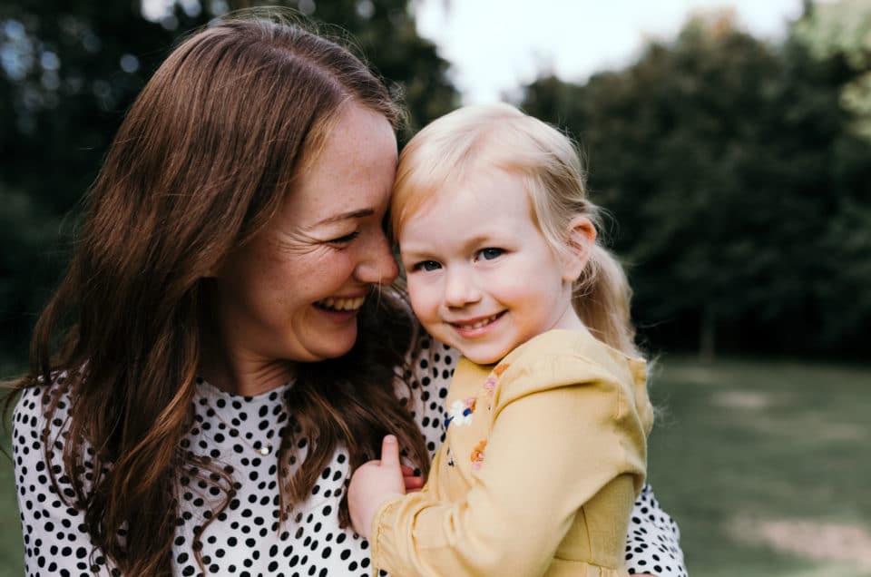 Mum holding girl smiling to her. Sunset family photoshoot in Basingstoke