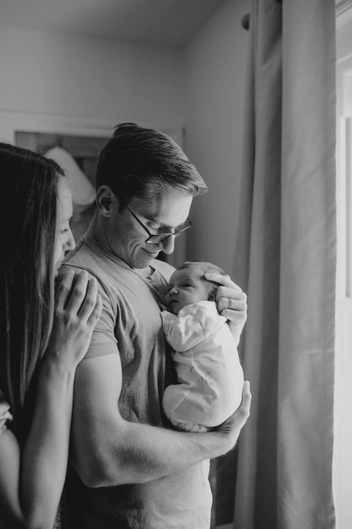 mum and dad are looking at their baby and cuddling. black and white in home photo session. Hampshire photo session. Basingstoke photographer. Ewa Jones Photography