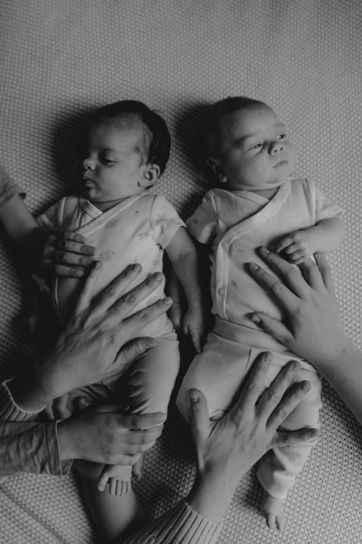 newborn photo session at home. black and white image of twin girls laying on the bed. in home natural newborn photo session. Hampshire newborn photographer. Ewa Jones Photography