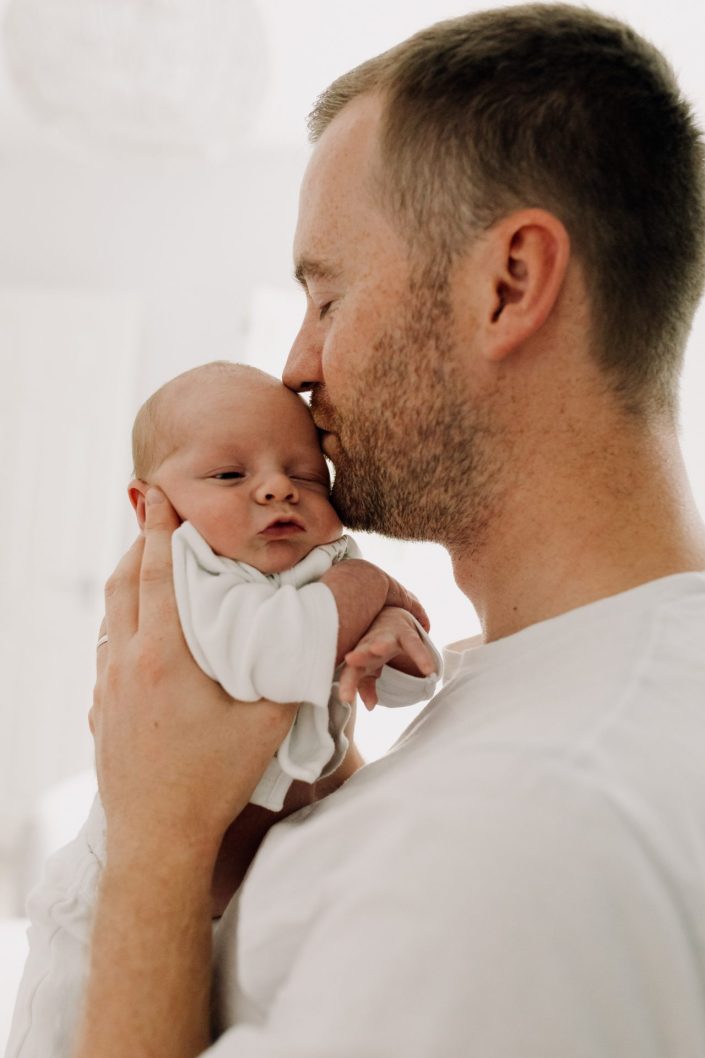 dad is kissing his baby in the head. Newborn photo shoot at home. Hampshire photo session. Ewa Jones Photography