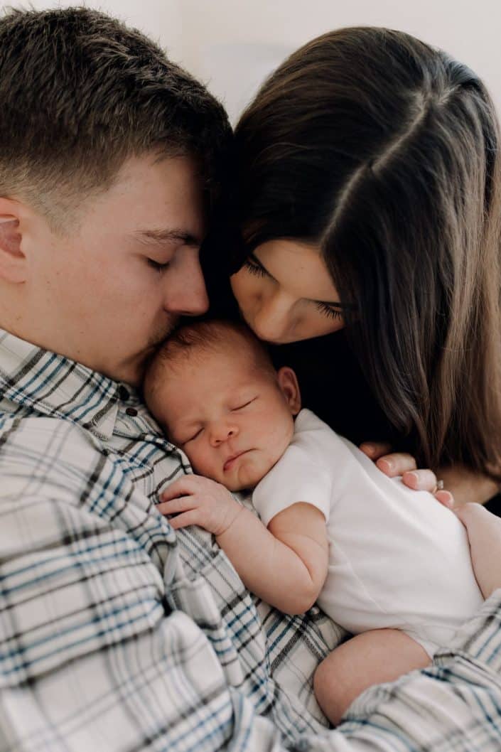 Mum and dad are kissing their baby girl. lovely intimate newborn photo session. Newborn shoot in Hampshire. Basingtoke newborn photo shoot. Ewa Jones Photography