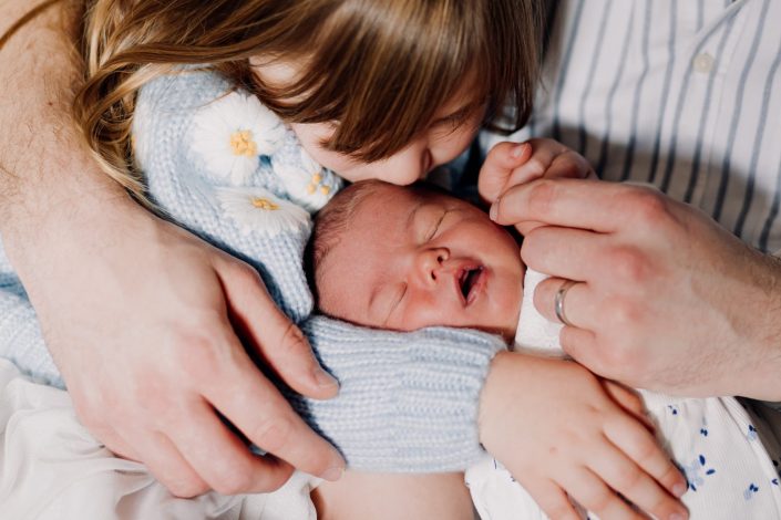 baby girl is being kissed by her big sister. newborn photo shoot at home. Hampshire photographer. Hampshire photo session. Ewa Jones Photography