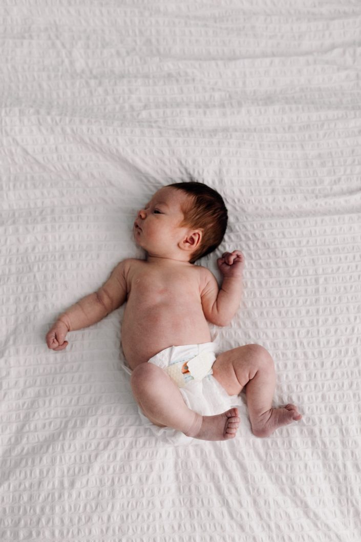 newborn baby girl is laying on bed. Hampshire newborn photo shoot. Basingstoke newborn photographer. Ewa Jones Photography