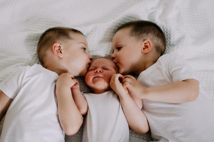 brothers are kissing their newborn baby brother. in home natural lifestyle photo session. Newborn photographer in Hampshire. Basingstoke newborn photo session. Ewa Jones Photography